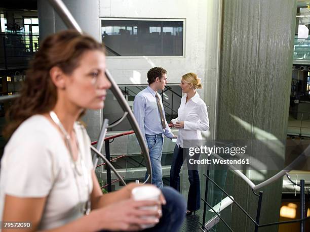 young woman listening to colleagues talking - eavesdropping stock pictures, royalty-free photos & images