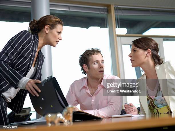 businesswoman and co-workers in office, discussing - exigir fotografías e imágenes de stock