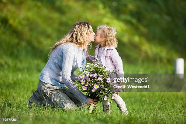 mother kissing daughter, holding bunch of flowers, side view - girl with legs open stock pictures, royalty-free photos & images