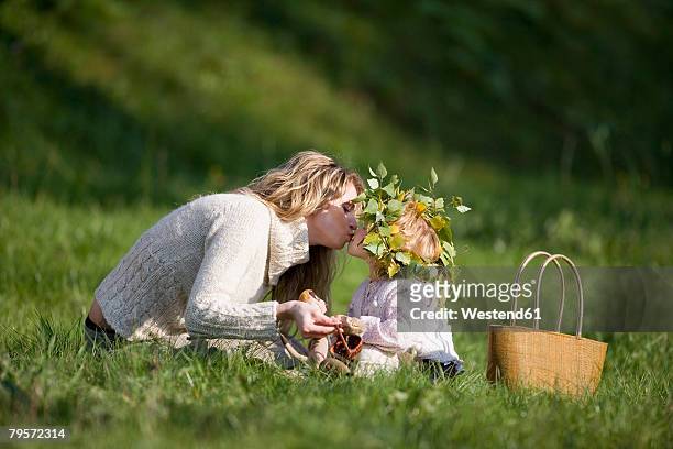 mother and daughter in meadow, doughter wearing wreath on head - haarkranz stock-fotos und bilder