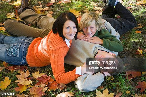 parents with son (10-12) lying in meadow, portrait, elevated view - 10 11 years stock pictures, royalty-free photos & images