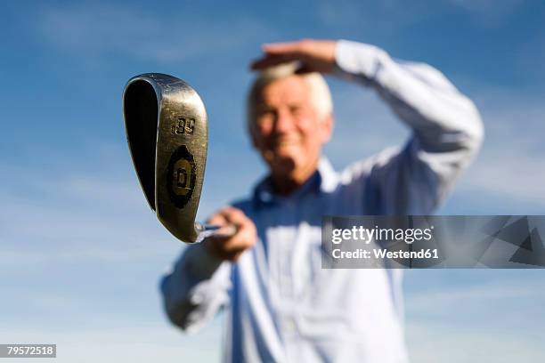 senior adult man holding golf club - senior golf swing stock pictures, royalty-free photos & images