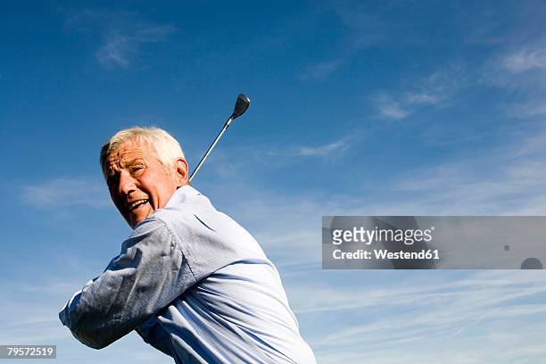 senior adult man holding golf club - senior golf swing stock pictures, royalty-free photos & images