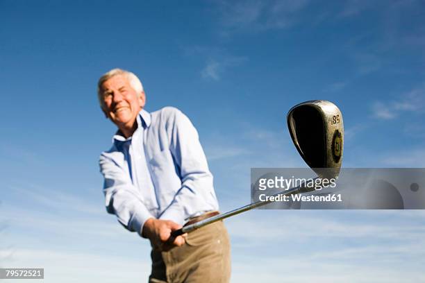 senior adult man holding golf club - senior golf swing stock pictures, royalty-free photos & images
