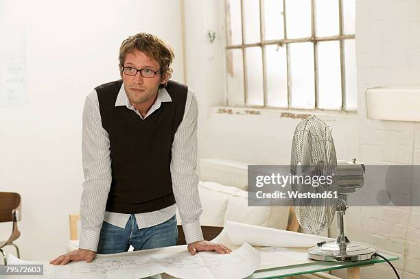 young man leaning on desk - portrait of pensive young businessman wearing glasses stock pictures, royalty-free photos & images