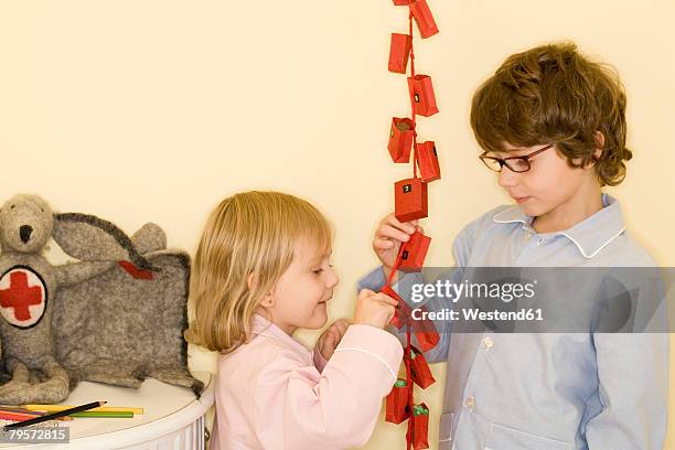 girl and boy standing by advent calendar - child with advent calendar stock pictures, royalty-free photos & images