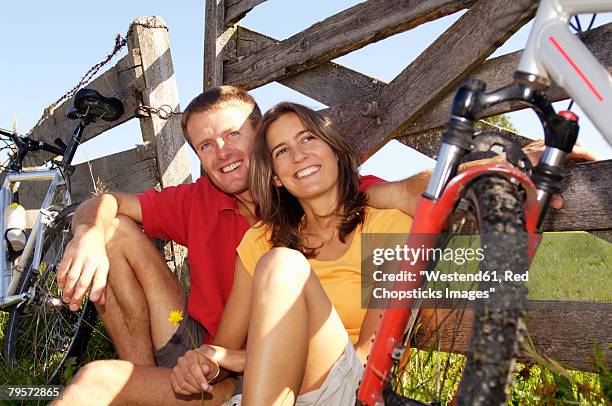 couple sitting in meadow, leaning on wooden railing - wellness kindness love stock pictures, royalty-free photos & images