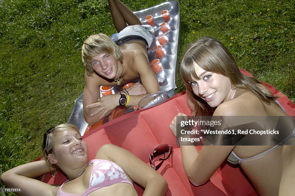 Young man and two young women lying on air mattress