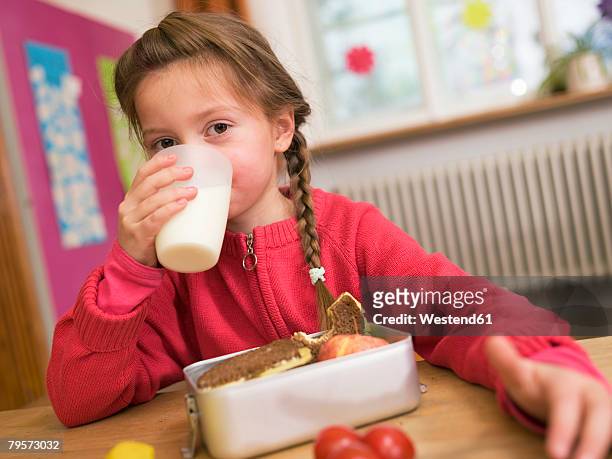 girl (4-7) sitting by desk, drinking glass of milk, portrait - kids kindness stock pictures, royalty-free photos & images