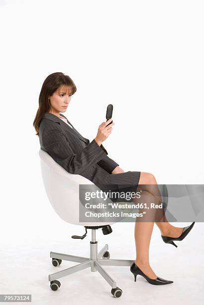 businesswoman sitting in chair, using mobile phone - posición descriptiva fotografías e imágenes de stock