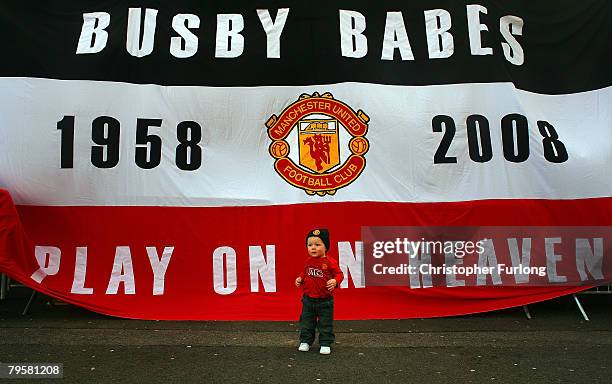 Young Manchester United fan poses in front of a banner for his mother to take a photo, as fans take part in a minute's silence to mark 50 years since...