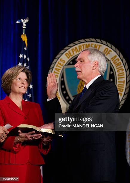 Secretary of Agriculture Edward Schafer takes his oath of office from Deputy Secretary of Agriculture Chuck Conner, as Schafer's wife Nancy holds a...