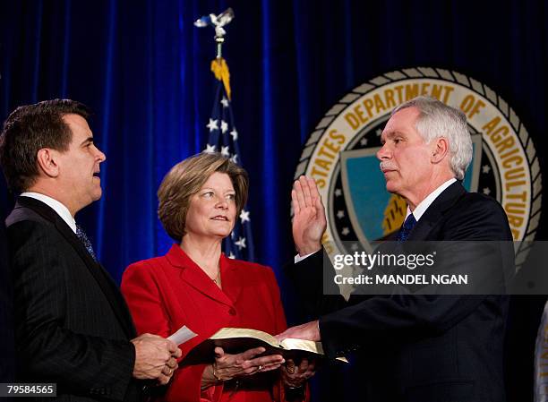 Secretary of Agriculture Edward Schafer takes his oath of office from Deputy Secretary of Agriculture Chuck Conner as Schafer's wife Nancy holds a...
