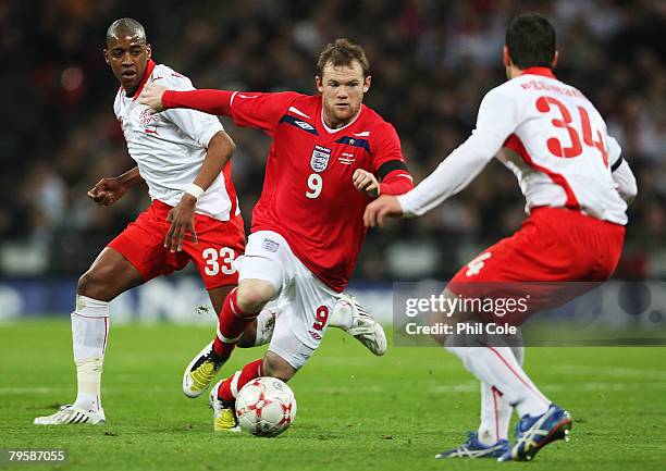 Wayne Rooney of England takes on Mario Eggimann and Gelson Fernandes of Switzerland during the international friendly match between England and...