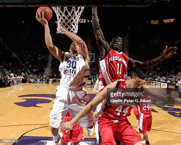 Forward Michael Beasley of the Kansas State Wildcats drives to the basket against pressure from Nebraska Cornhuskers guard Ade Dagunduro and guard...