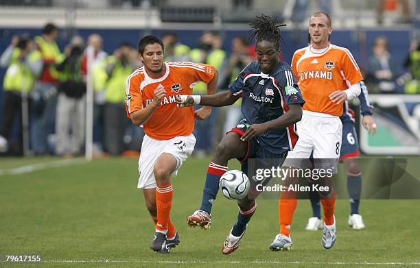 Shalrie Joseph of the New England Revolution moves the ball away from Brian Ching of the Houston Dynamo during the MLS Cup match at Pizza Hut Park in...