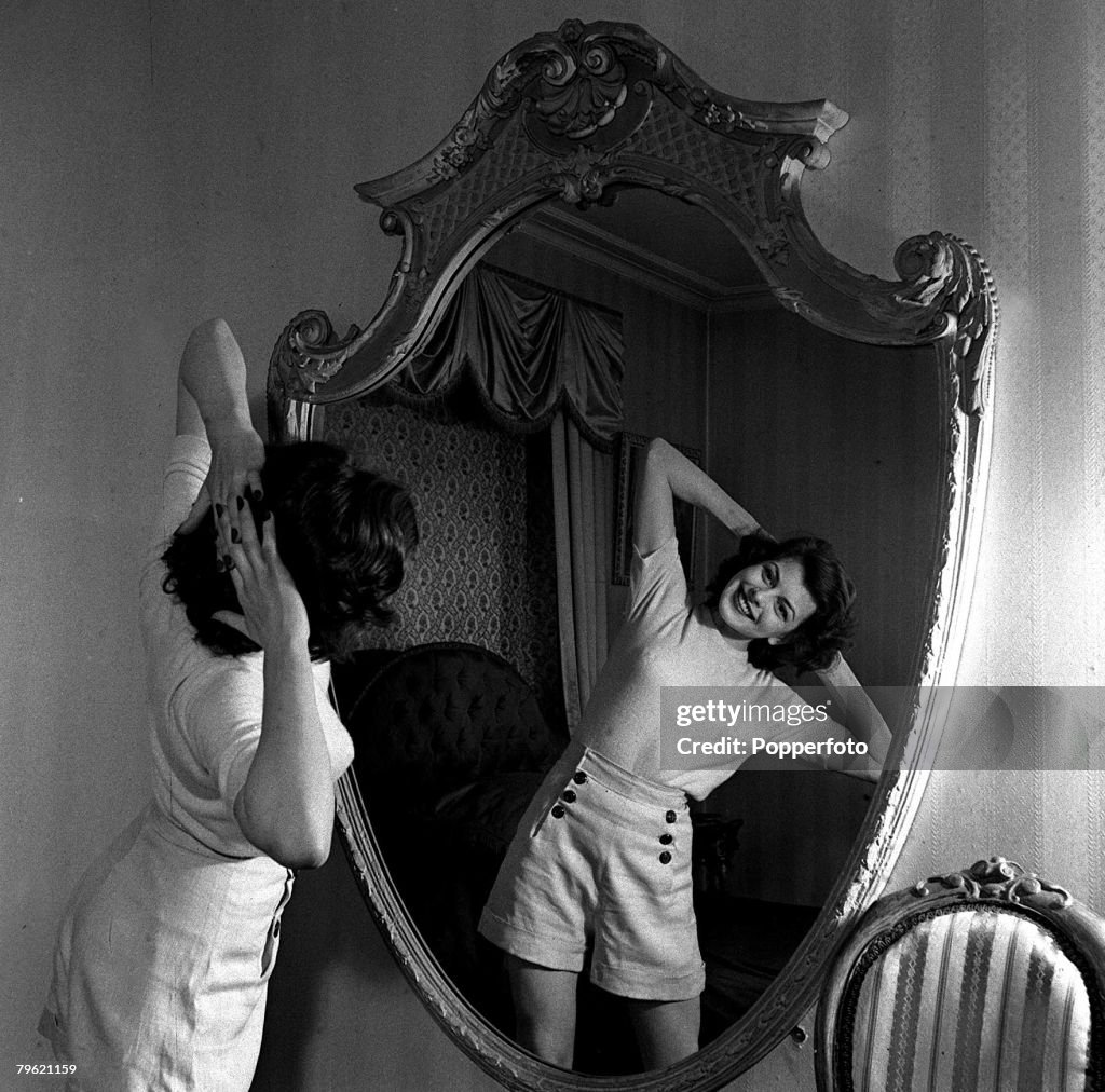 1951. A picture of film actress Joan Rice stretching in front of a mirror.