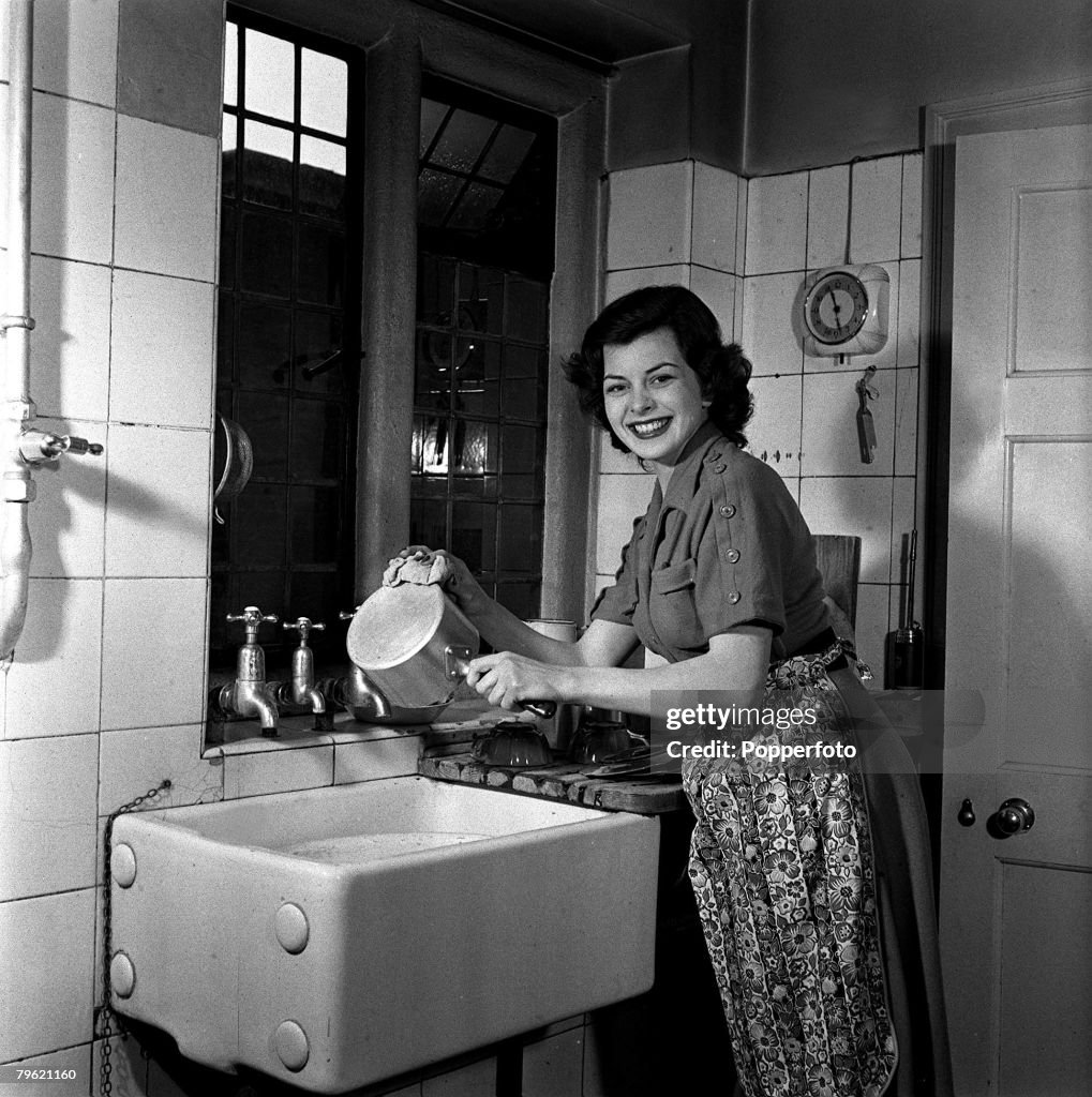 1951. A picture of film actress Joan Rice washing a saucepan in the sink.