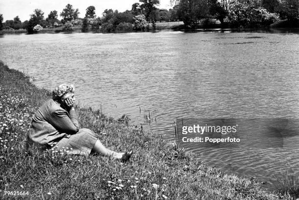 English writer and novelist Agatha Christie seated on the banks of the River Thames in the grounds of her home, Winterbrook House near Wallingford,...