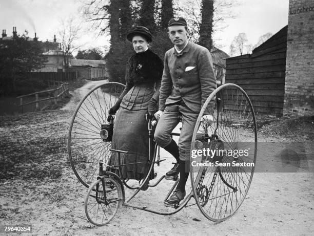 Young couple out cycling in Putney, on a tandem penny farthing tricycle, circa 1890.