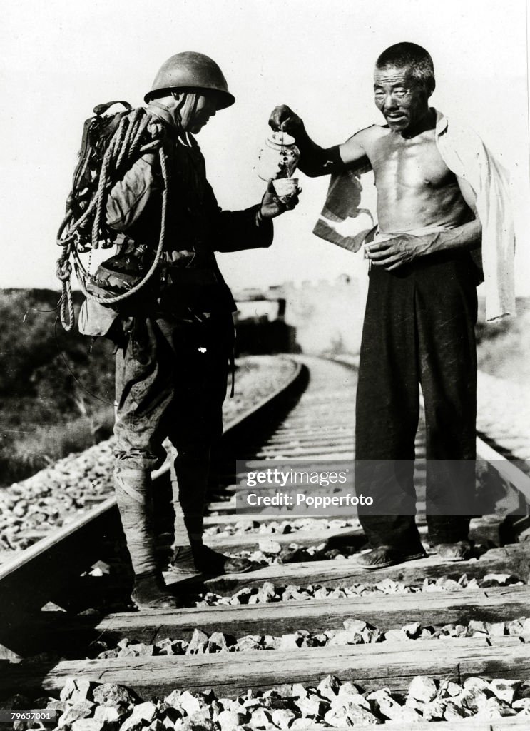 War and Conflict, 2nd Sino-Japanese War, (1937-1945), A Japanese railroad guard is refreshed by a cup of tea from a friendly chinese near Tientsin, Northern China, Following the two countries conflict at the end of the 19th century, further hostilities de