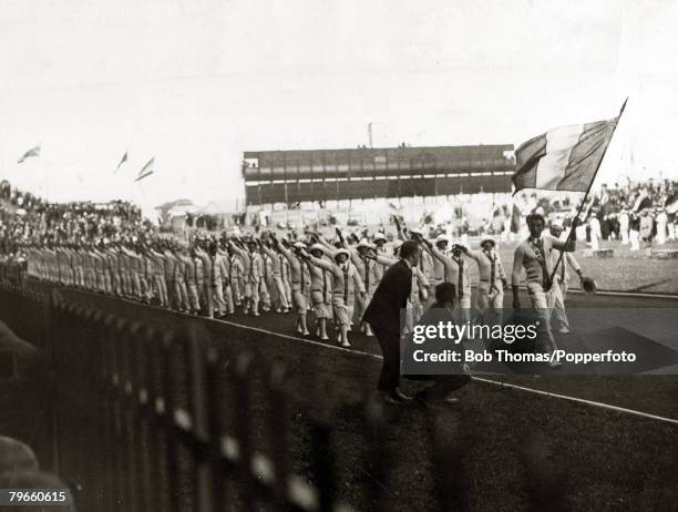 Spectators in the stands watch athletes from the host nation France take part in the Parade of Nations during the opening ceremony of the 1924 Summer...