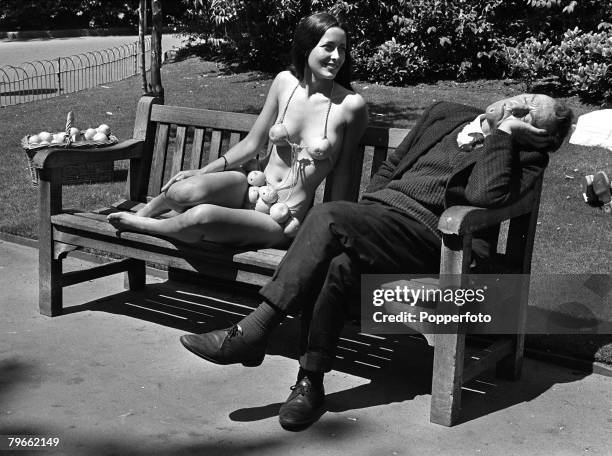 London, England, 13th July 1971, A young model wearing a bikini made of orange peel fails to awaken a sleeping man on a park bench in a London park,...