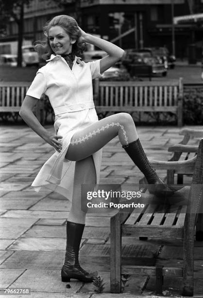 London, England, 10th September 1970, A model stands by a bench with her foot placed on the armrest to display the split skirt and patterned tights...