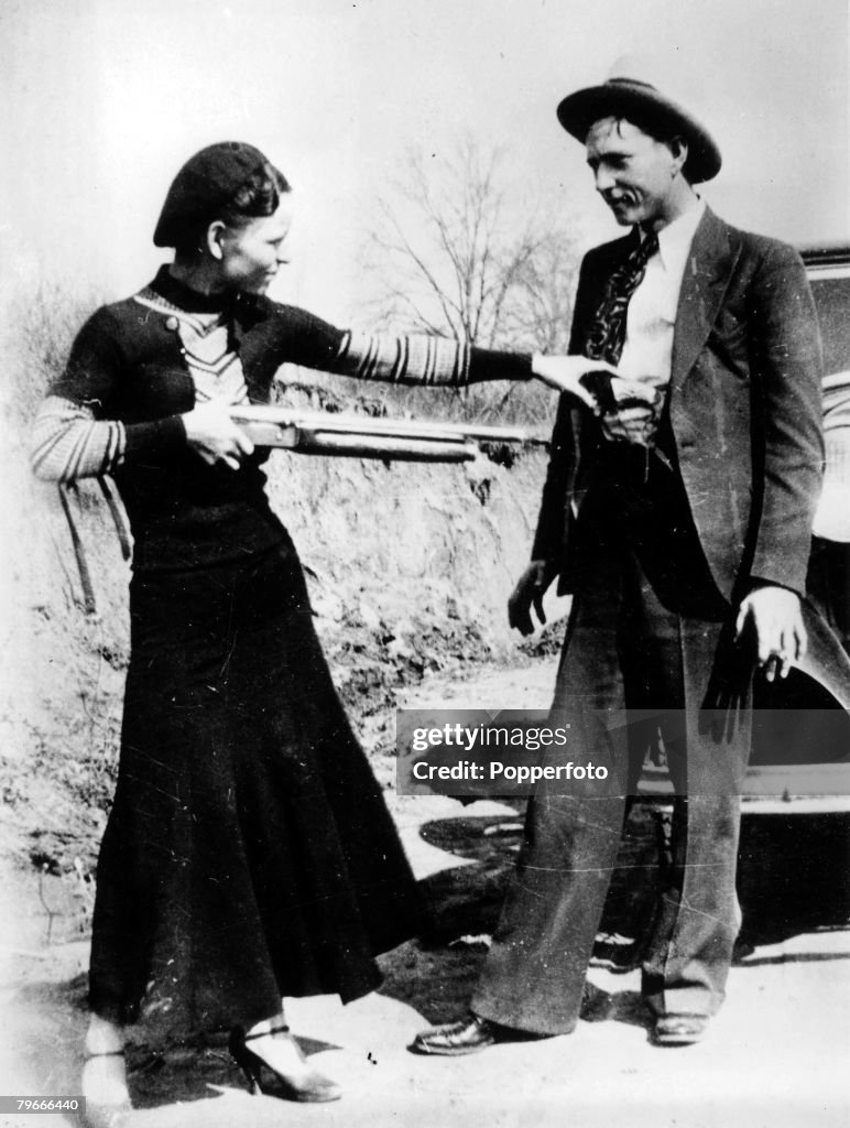 Circa 1932, USA, Bonnie Parker points a shotgun at boyfriend Clyde Barrow, together they found infamy as ,Bonnie and Clyde from August 1932 until they were killed at a Police roadblock by Police in May 1934, Despite their popular romantic image, they and 