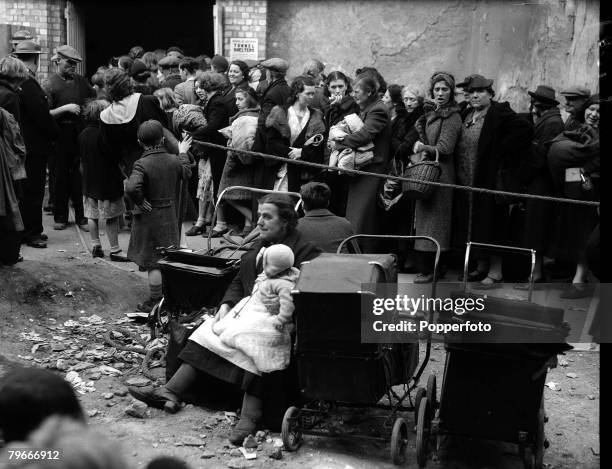 September 26th 1940, A mother and her baby and children in prams wait beside a queue for admittance to a deep air raid shelter in London during The...