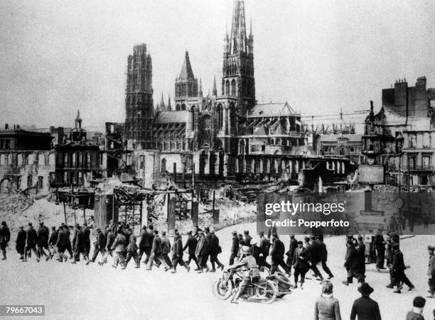 French Prisoners of war are marched through Rouen where they are set the task of clearing up the damage and debris left by the German invasion of...