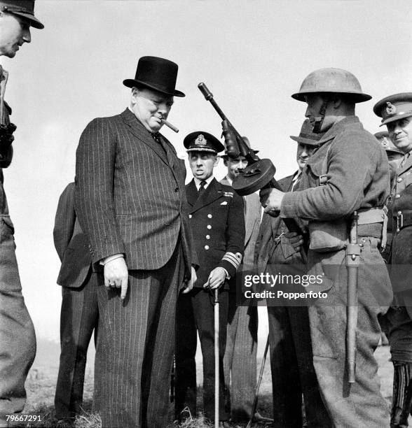 British Prime Minister Winston Churchill is shown an American Thompson submachine gun during an inspection of coastal fortifications and defences on...