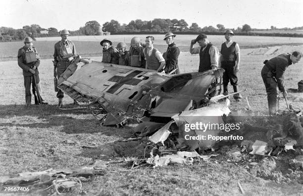 Members of the Home Guard and local workers examine the wreckage of a Messerschmitt Bf 109 of the German Luftwaffe, which was shot down in flames...