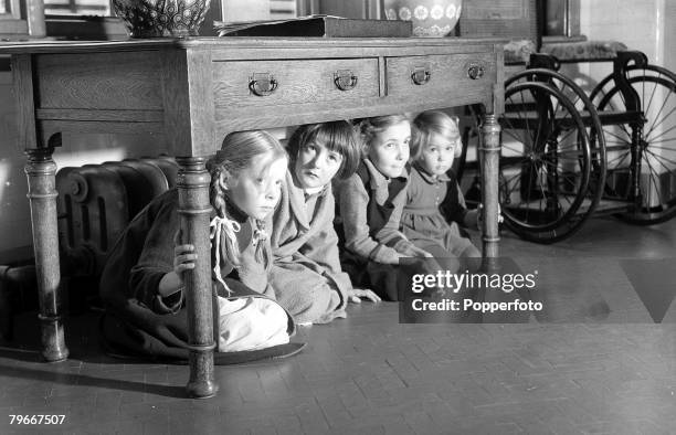 World War Two, England, 13th October Four little girls shelter from an air raid under the table at the National Children's Home and Orphanage during...