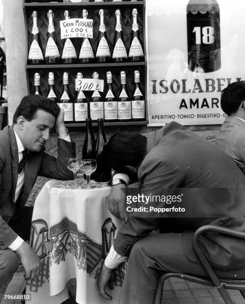 Classic Collection, Page 86 Frascati, Italy, 23rd November 1957, Two men sit at a table, one with his head slumped on the table and the other...