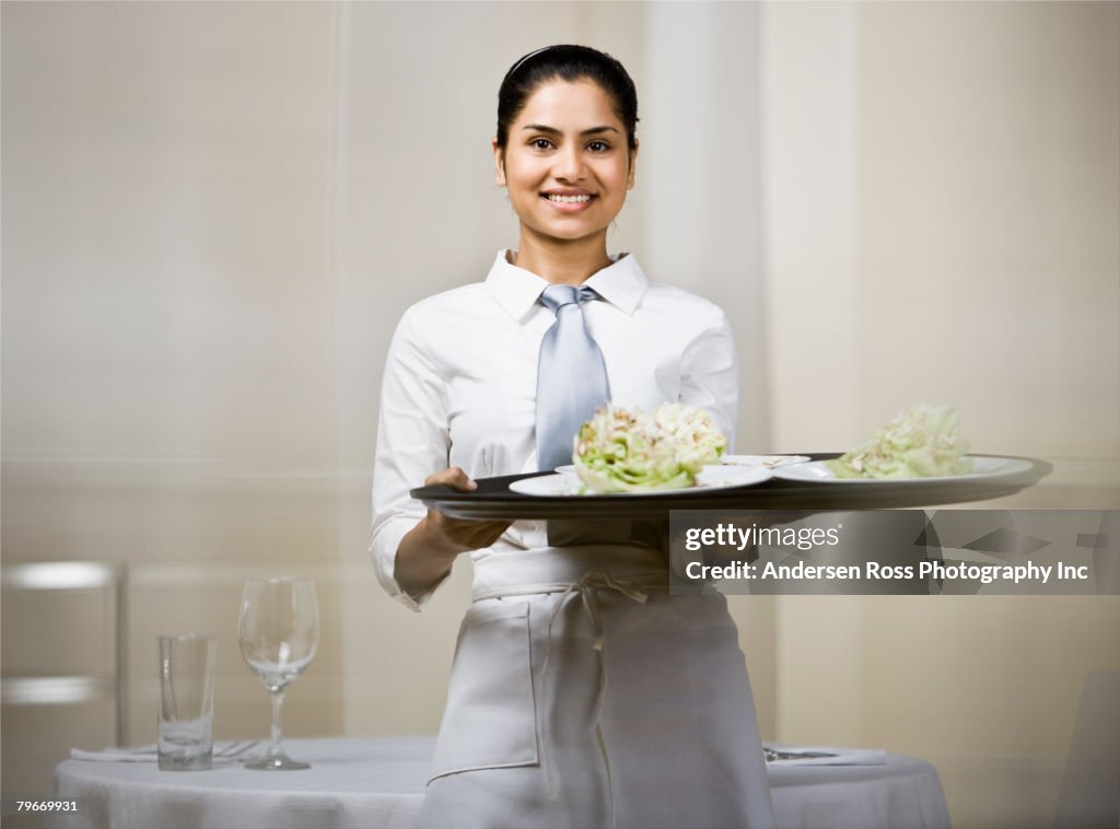 Indian waitress carrying tray of food