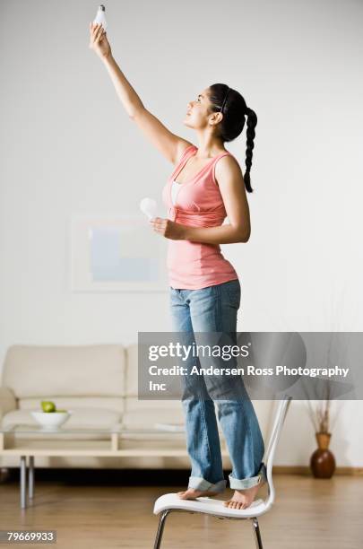 indian woman changing light bulb - person reaching stock pictures, royalty-free photos & images