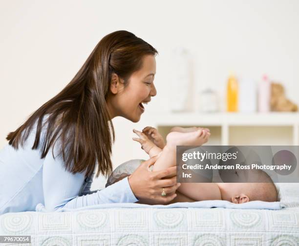 asian mother playing with baby - mum changing nappy stock-fotos und bilder