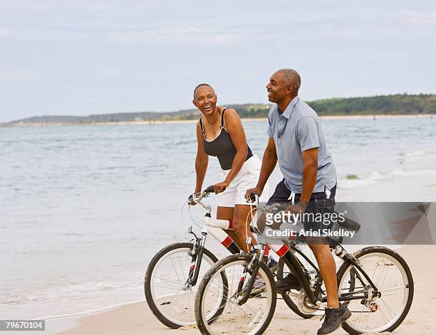 senior african american couple riding bicycles on beach - couple cycling stock pictures, royalty-free photos & images