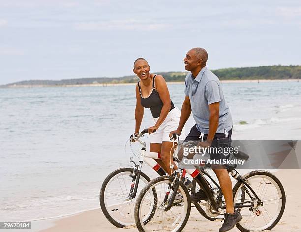 senior african american couple riding bicycles on beach - black woman riding bike imagens e fotografias de stock