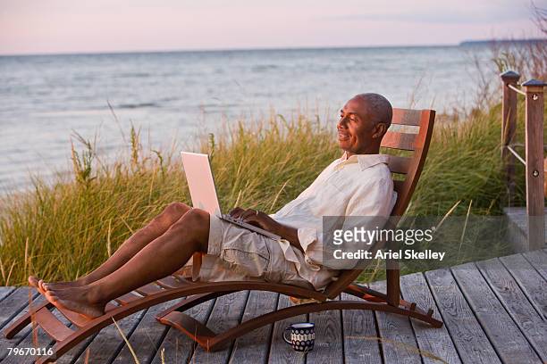 senior african american man typing on laptop - using laptop outside stock pictures, royalty-free photos & images