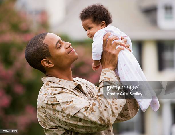 african american military father holding baby - marine camouflage stockfoto's en -beelden