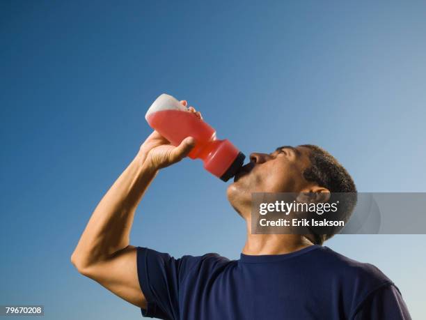 hispanic man drinking from squeeze bottle - energydrink stock-fotos und bilder