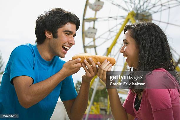 multi-ethnic couple eating hot dog at carnival - hot middle eastern girls stock-fotos und bilder