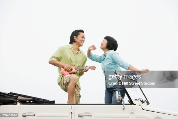 asian couple dancing in convertible - asian couple car stock pictures, royalty-free photos & images
