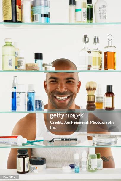 african american man looking in medicine cabinet - bathroom cabinet stock pictures, royalty-free photos & images