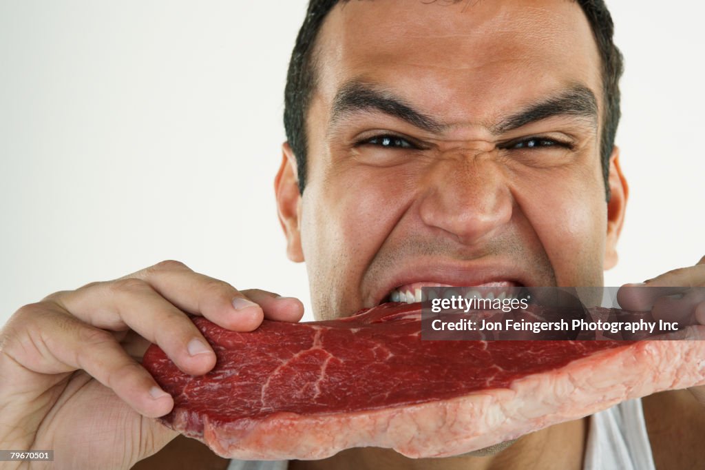 Hispanic man biting raw beef