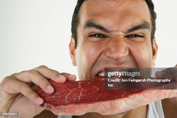 hispanic man biting raw beef - red meat stock pictures, royalty-free photos & images