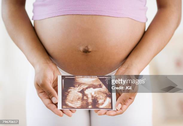 pregnant african american woman holding ultrasound printout - embarazada fotos fotografías e imágenes de stock