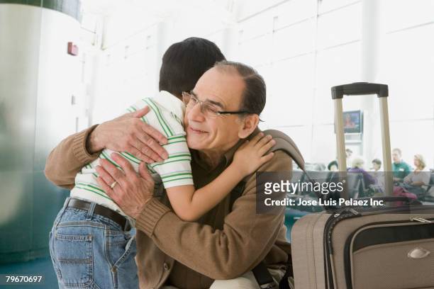 hispanic grandfather and grandson hugging at airport - reunion stock pictures, royalty-free photos & images